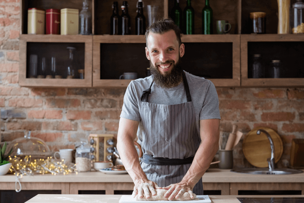 Smiling chef kneading dough in the kitchen after taking online Patisserie courses