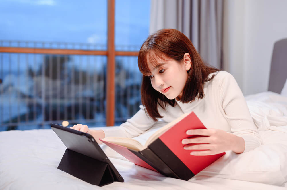 Woman using a traditional book with online learning sources