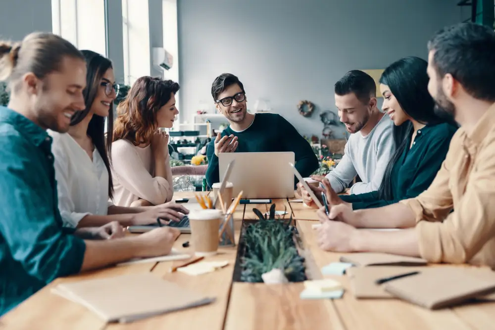 A team leader sitting at the head of the table collaborating with other employees