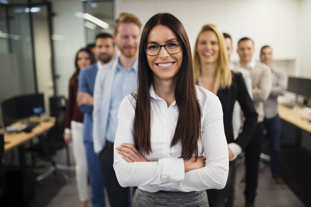 smiling young woman in leadership position with blurred colleagues in background