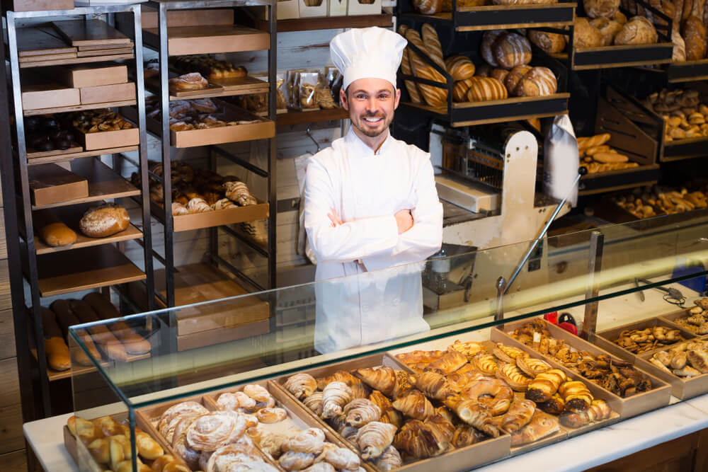 professional baker posing with pastries in a bakery