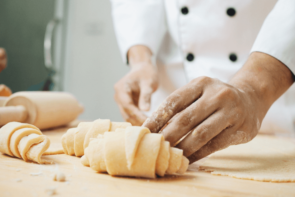 closeup of pastry chef rolling croissant
